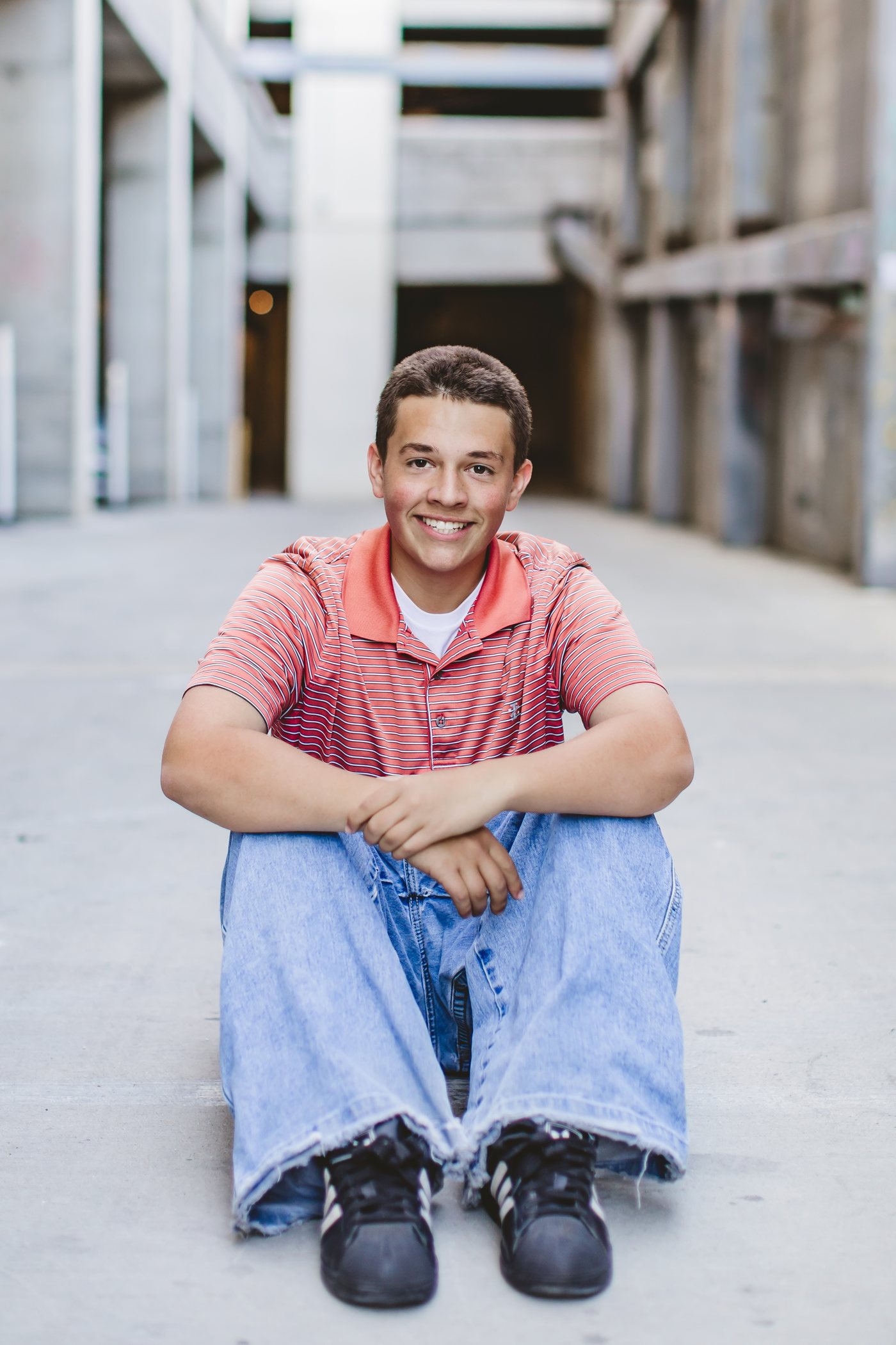 Isaac sitting outdoors in a salmon striped shirt