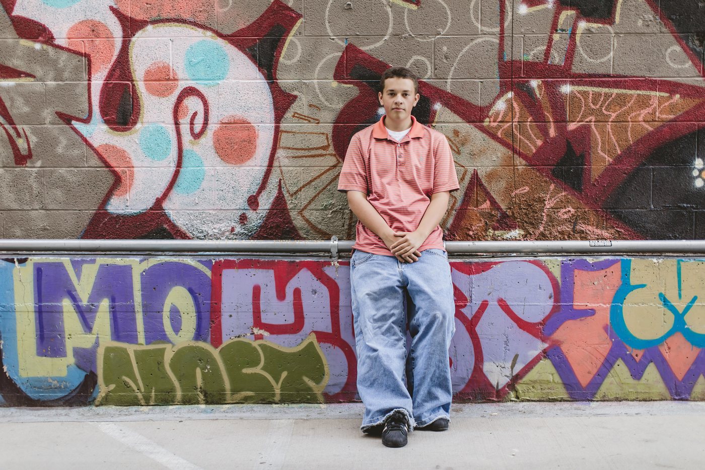 Isaac seated in front of red and blue mural art
