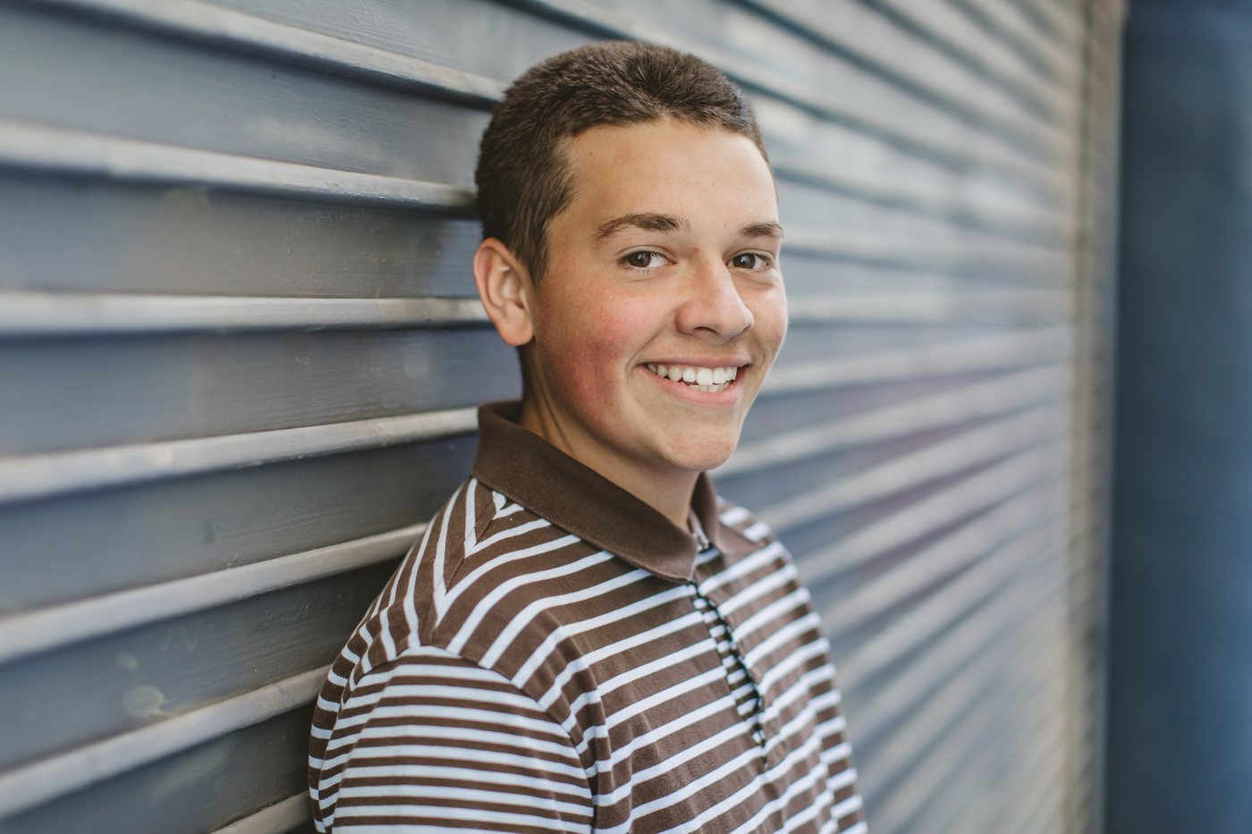 Isaac smiling by a metal wall