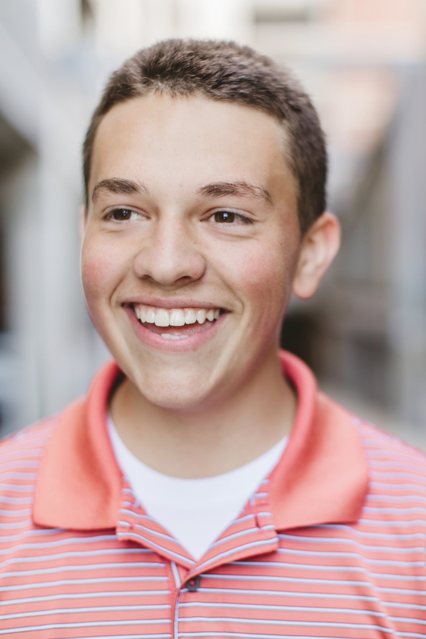 Isaac smiling in a salmon striped shirt