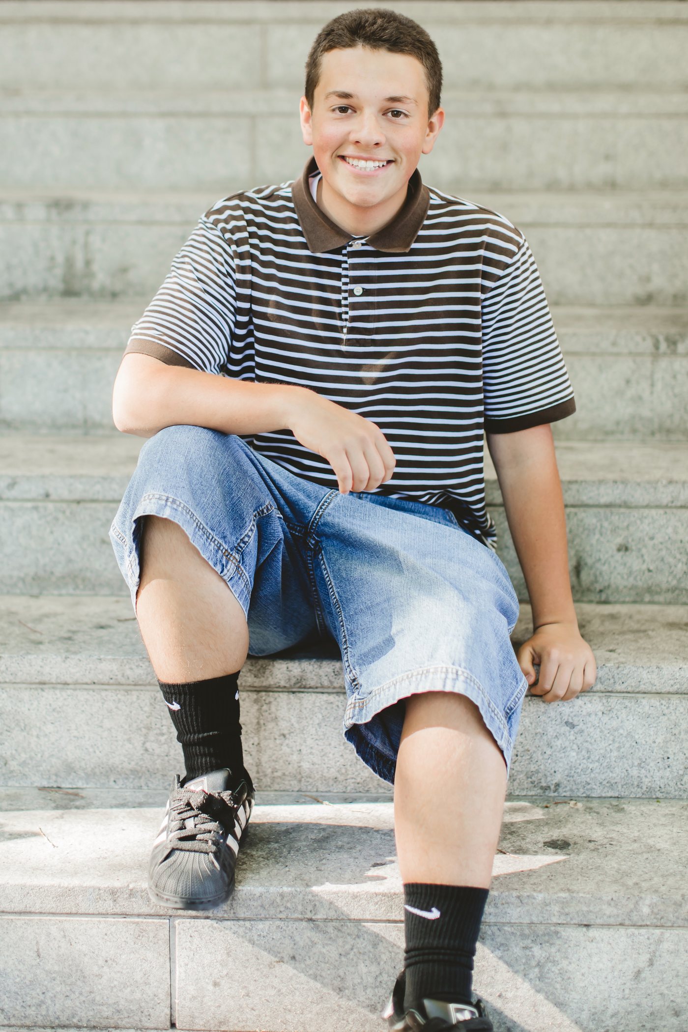Isaac sitting on outdoor steps in a striped shirt