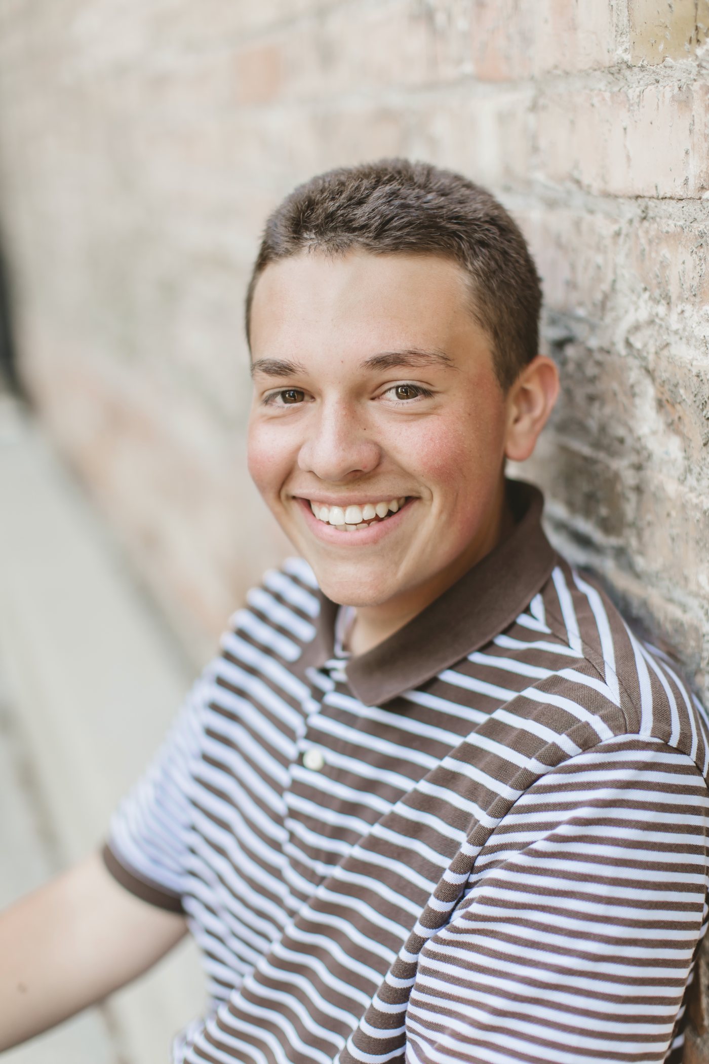 Isaac smiling against a light brick wall