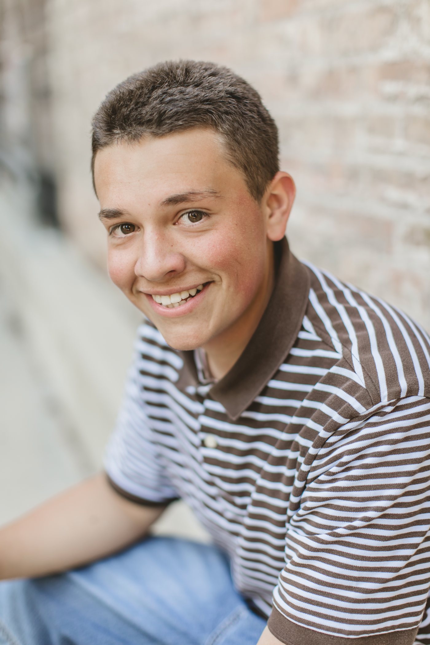 Isaac seated in front of a brick wall