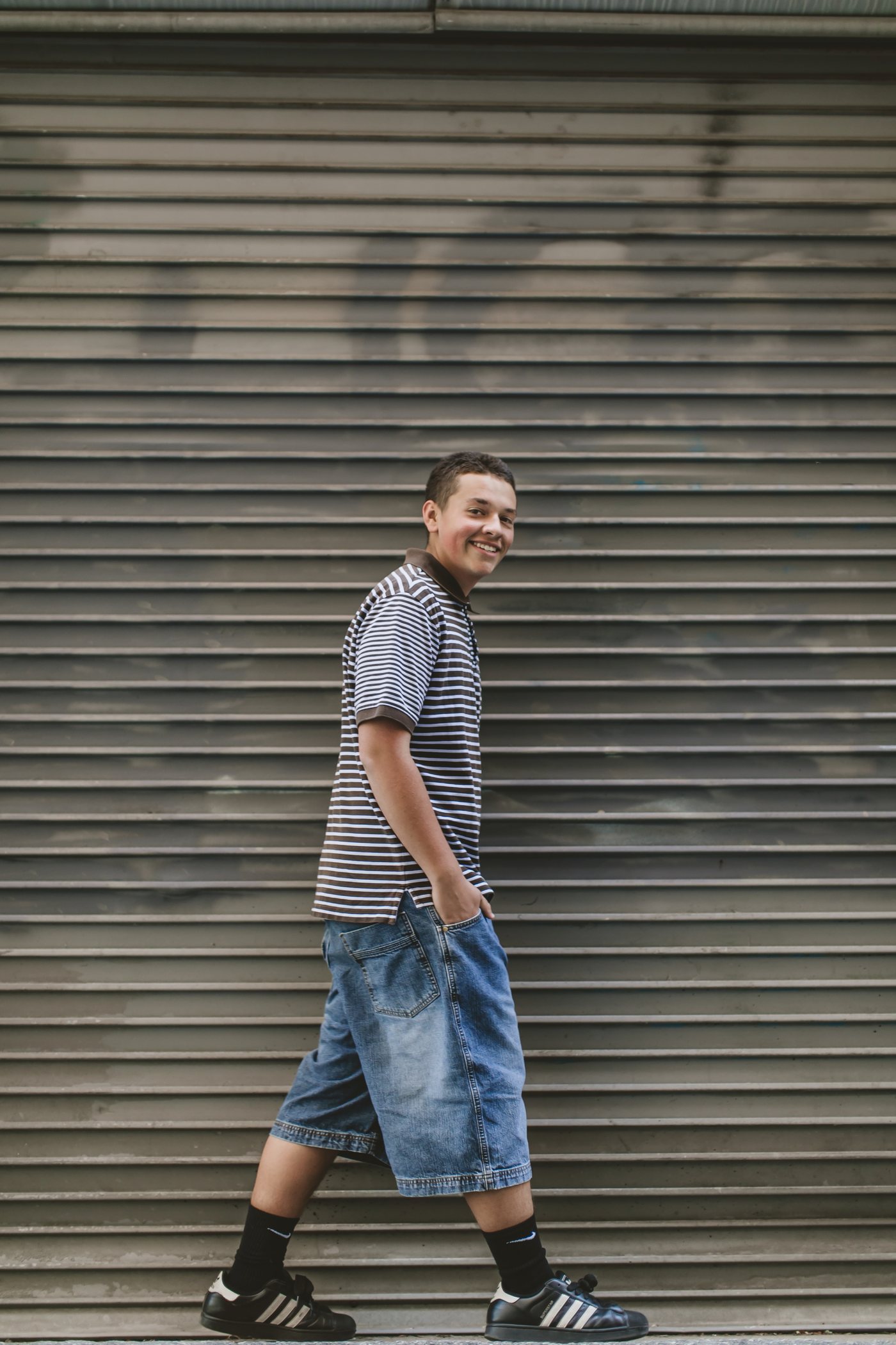 Isaac walking by a corrugated metal wall